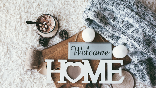 A warmly lit living room invites with a plush sofa adorned with textured throw pillows and a cozy knit blanket draped over one corner