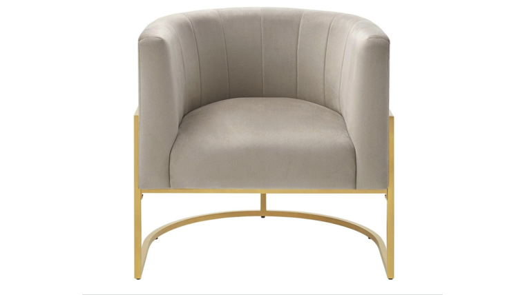 Taupe velvet barrel accent chair with gold accents and a hidden, storable ottoman. Features flared arms, foam-filled seat and back for comfort, a solid wood frame with a sled base for stability, and includes toss pillows for added comfort. The ottoman conveniently tucks under the chair to save space, creating a stylish, space-saving solution for any room.