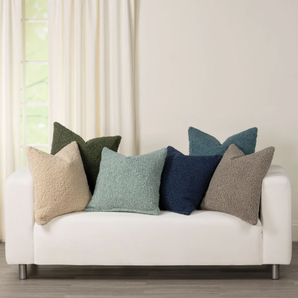Beige bouclé throw pillow with looped textured fabric, square accent pillow on a neutral-toned sofa