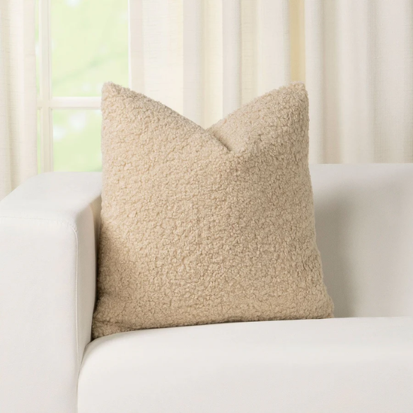 Beige bouclé throw pillow with looped textured fabric, square accent pillow on a neutral-toned sofa