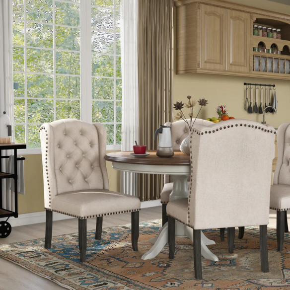 Set of two beige upholstered dining chairs with wingback design, button-tufted backrest, nailhead trim, and espresso-finished wooden legs