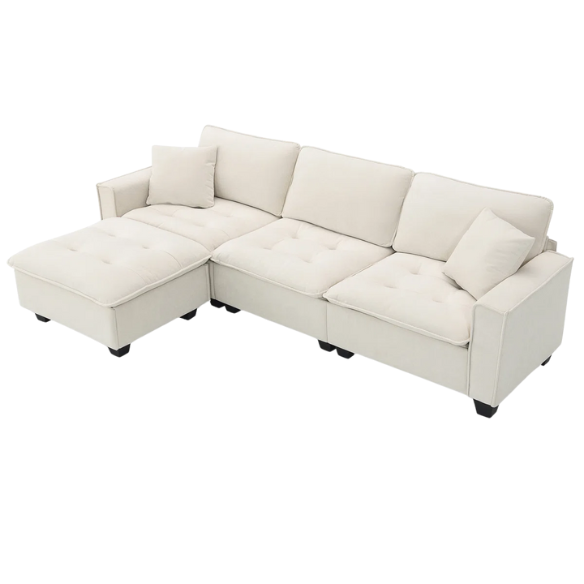 Beige suede L-shaped sectional sofa with removable ottoman, tufted seat cushions, and two matching accent pillows