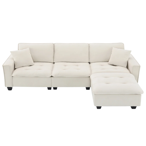 Beige suede L-shaped sectional sofa with removable ottoman, tufted seat cushions, and two matching accent pillows