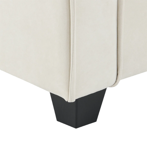 Beige suede L-shaped sectional sofa with removable ottoman, tufted seat cushions, and two matching accent pillows