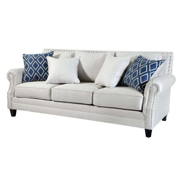 Beige tufted linen sofa with rolled arms, nailhead trim, tapered wooden legs, and accent pillows in transitional style.