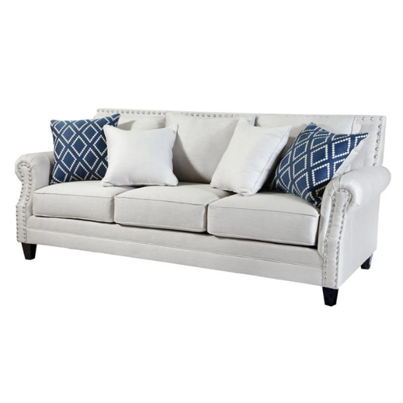 Beige tufted linen sofa with rolled arms, nailhead trim, tapered wooden legs, and accent pillows in transitional style.