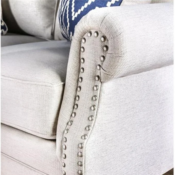 Beige tufted linen sofa with rolled arms, nailhead trim, tapered wooden legs, and accent pillows in transitional style.