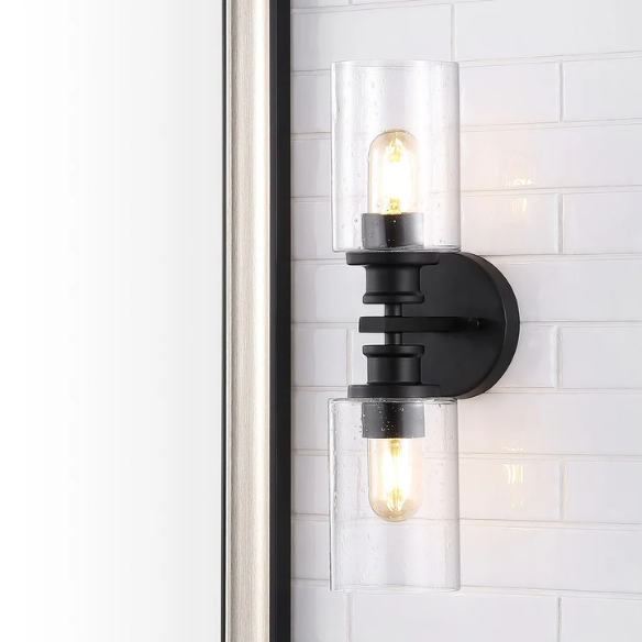 Art Deco-style black wall sconce with dual clear seeded glass cylinder shades and Edison-style LED bulbs, suitable for bathroom or hallway lighting