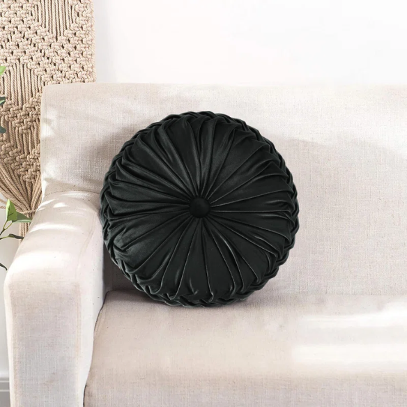 Black velvet round throw pillows with hand-sewn pleats and central button, set of two 14.5-inch plush decorative cushions styled on a modern neutral sofa.