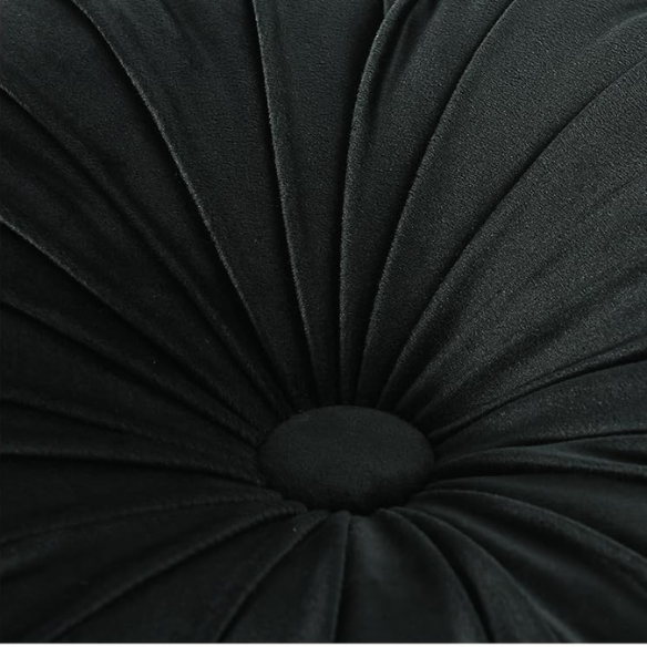 Black velvet round throw pillows with hand-sewn pleats and central button, set of two 14.5-inch plush decorative cushions styled on a modern neutral sofa.