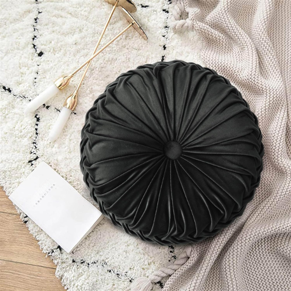 Black velvet round throw pillows with hand-sewn pleats and central button, set of two 14.5-inch plush decorative cushions styled on a modern neutral sofa.