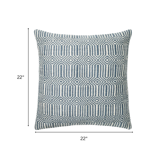 Blue and cream geometric throw pillow on a modern outdoor chair in a patio setting