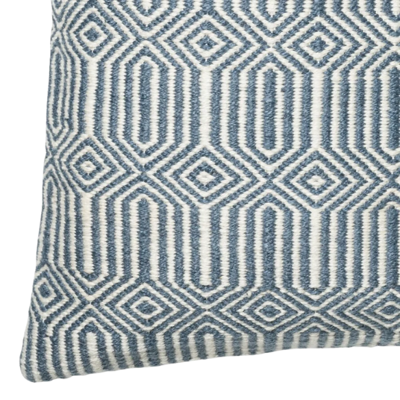 Blue and cream geometric throw pillow on a modern outdoor chair in a patio setting