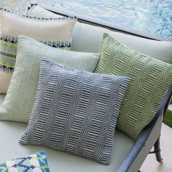 Blue and cream geometric throw pillow on a modern outdoor chair in a patio setting