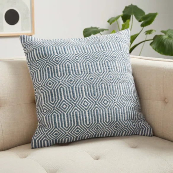 Blue and cream geometric throw pillow on a modern outdoor chair in a patio setting