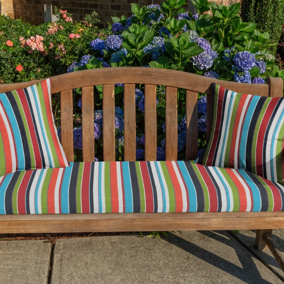Striped accent pillow in blue, red, white, green, and black – reversible, weather-resistant, and overstuffed with plush polyester fill for indoor and outdoor use on patios, decks, or couches.