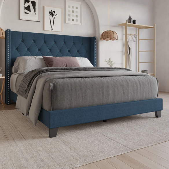 Blue upholstered full-size bed with tufted wingback headboard and nailhead trim