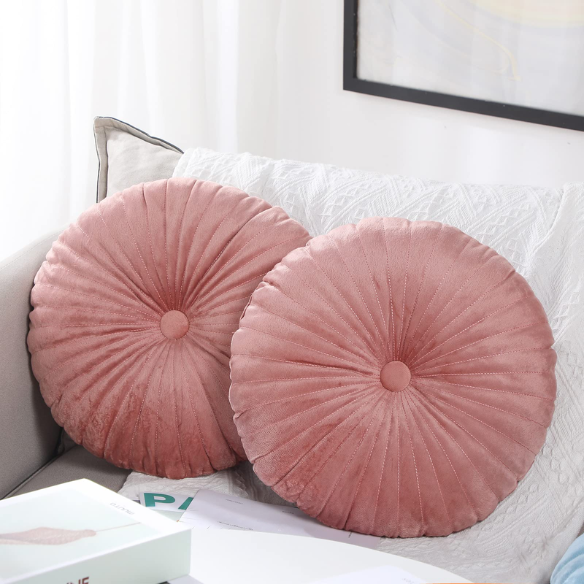 Blush velvet round throw pillow with button closure and pleated design, soft cotton fill for added comfort and support, perfect for home décor and sofa.