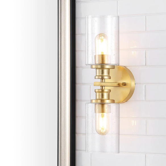 Rich brass wall sconce with dual clear seeded glass cylinder shades and Edison-style LED bulbs, perfect for upscale bathroom or hallway lighting