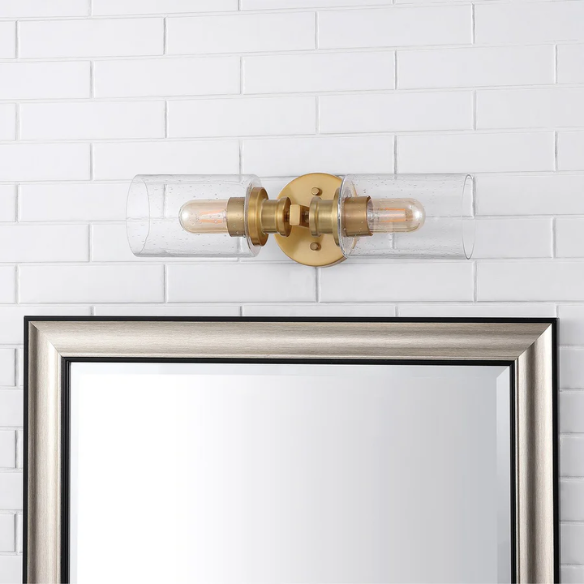 Rich brass wall sconce with dual clear seeded glass cylinder shades and Edison-style LED bulbs, perfect for upscale bathroom or hallway lighting