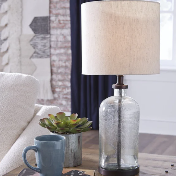 Bronze-tone seeded glass table lamp with beige fabric drum shade, featuring a metal base and compact design for modern farmhouse or industrial interiors