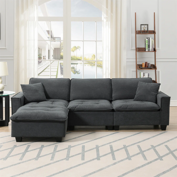 Charcoal grey suede L-shaped sectional sofa with tufted cushions, reversible chaise, removable ottoman, and two matching throw pillows