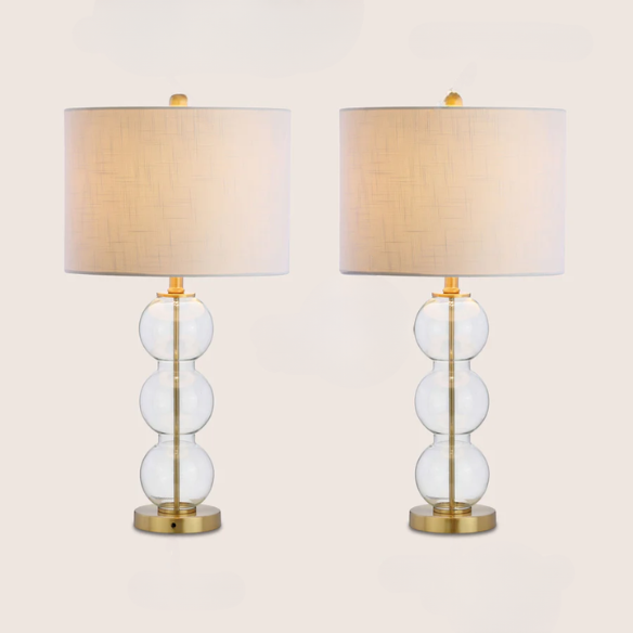 Set of 2 contemporary table lamps with clear glass triple-sphere base, gold accents, and white linen drum shade – modern glam bedside or living room lighting