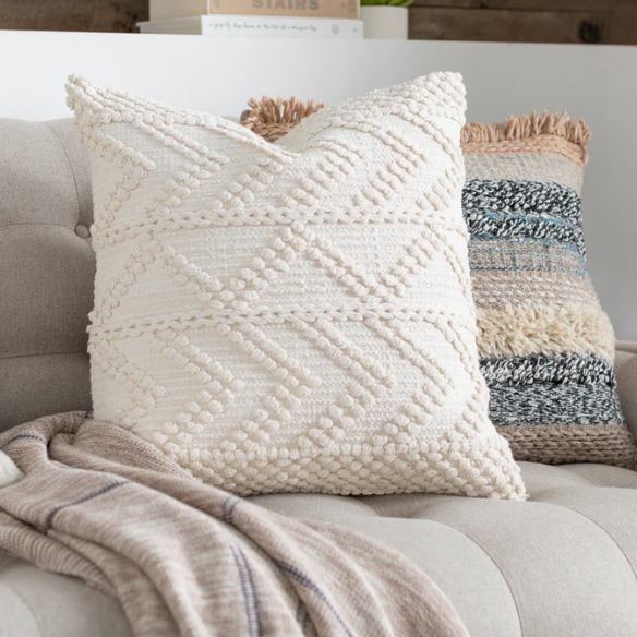 Cream handwoven boho throw pillow with chevron texture on a modern neutral-toned sofa