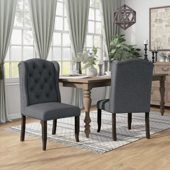 Set of two dark grey wingback farmhouse dining chairs with tufted backs, brass nailhead trim, and espresso-finished wooden legs