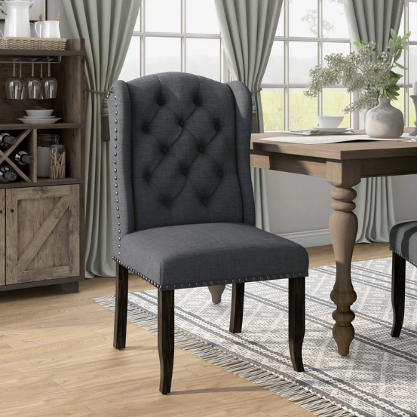 Set of two dark grey wingback farmhouse dining chairs with tufted backs, brass nailhead trim, and espresso-finished wooden legs