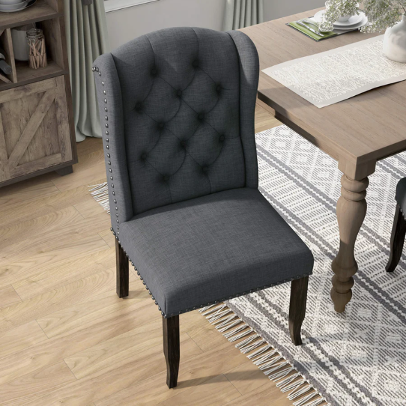 Set of two dark grey wingback farmhouse dining chairs with tufted backs, brass nailhead trim, and espresso-finished wooden legs