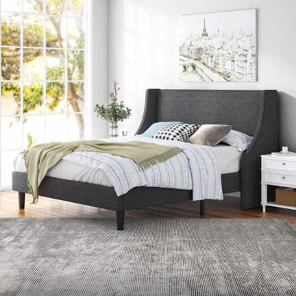 Dark grey upholstered queen platform bed with wingback headboard, slatted base, and black tapered legs – no box spring required