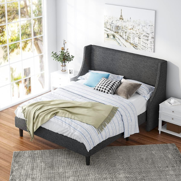 Dark grey upholstered queen platform bed with wingback headboard, slatted base, and black tapered legs – no box spring required