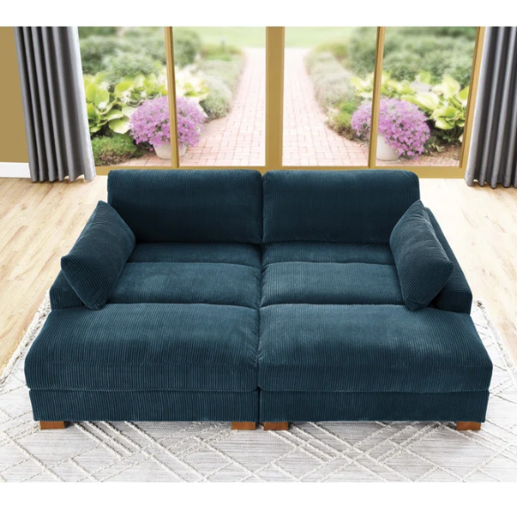 Deep blue corduroy convertible sleeper sofa with adjustable headrest, twin bed functionality, and mid-century wood legs