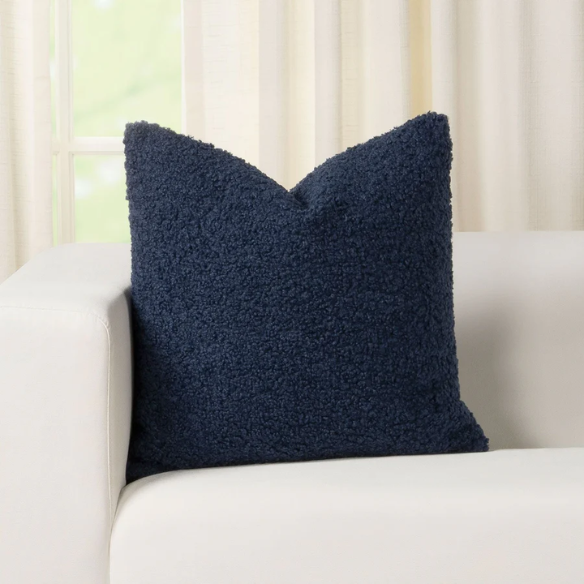 Deep navy blue bouclé throw pillow with looped texture, square accent pillow on a modern sofa