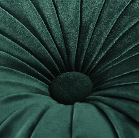 Emerald green velvet round throw pillows with hand-pleated detail and central button, 14.5-inch set of two on a white sofa in a stylish living room.