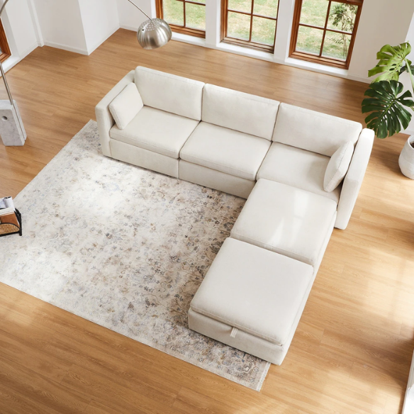 Beige five-piece modular sectional sofa with wide chenille-upholstered seats, two gas-lift storage ottomans, and reversible cushions — a modern and comfortable centerpiece for any living room.
