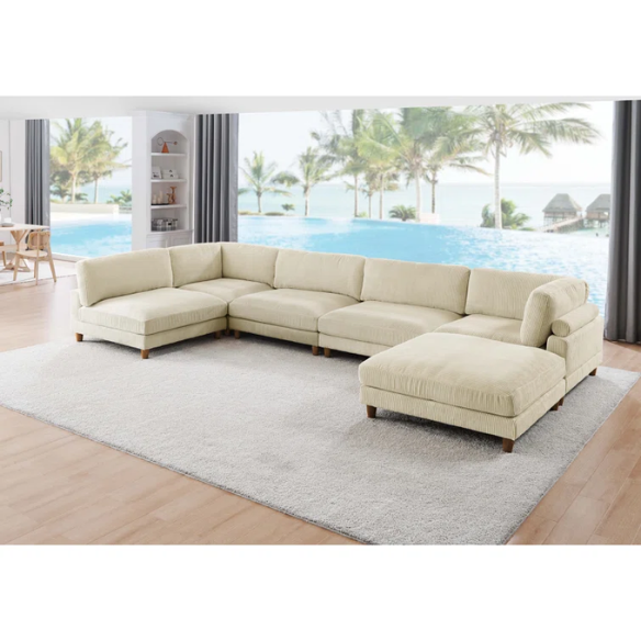 Beige modular sectional sofa with corduroy upholstery, removable cushions, and matching ottoman – seats six in a modern L-shaped or U-shaped layout with solid wood legs.
