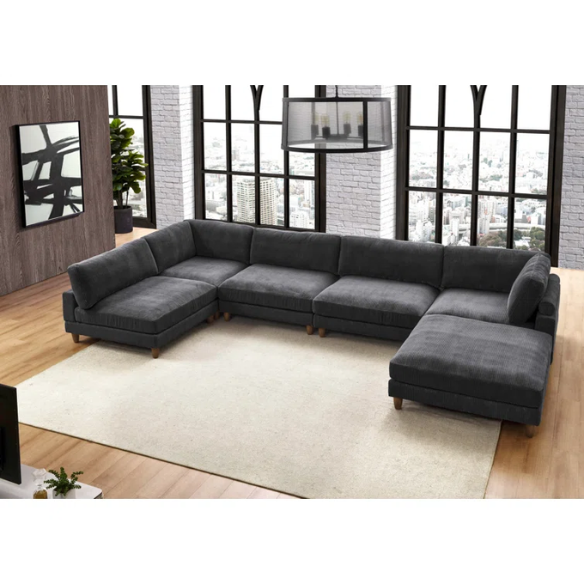 Dark grey modular sectional sofa with soft corduroy upholstery, matching ottoman, and removable cushions — seats six with flexible L- or U-shaped configurations.