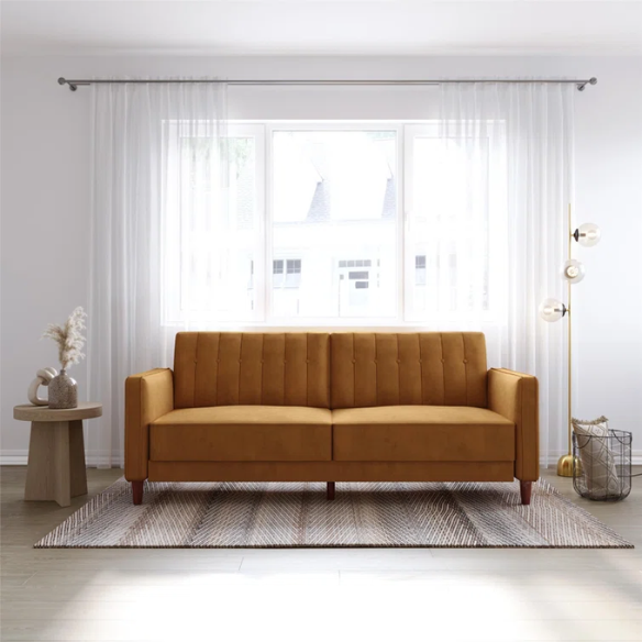 Golden brown velvet convertible sofa with square arms and vertical tufting, featuring split-back design, wood tapered legs, and fold-out support legs for twin bed conversion.