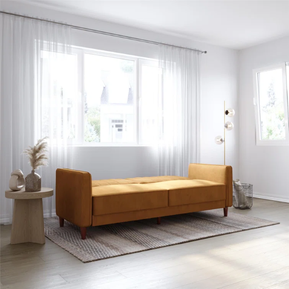 Golden brown velvet convertible sofa with square arms and vertical tufting, featuring split-back design, wood tapered legs, and fold-out support legs for twin bed conversion.