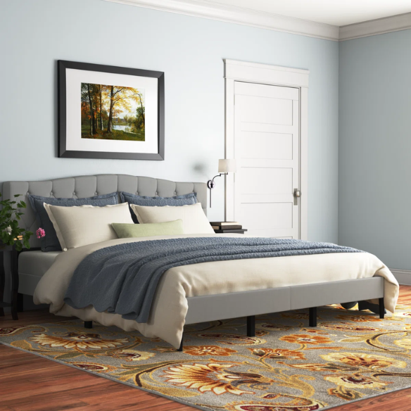 Grey upholstered king-size platform bed with tufted camelback headboard, solid wood slats, and center support legs