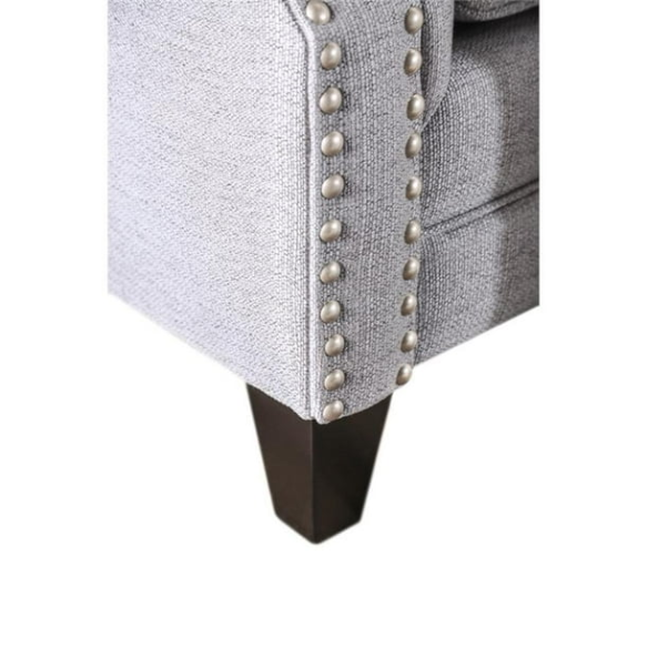 Grey tufted linen sofa with rolled arms, nailhead trim, tapered wooden legs, and accent pillows in a transitional design.