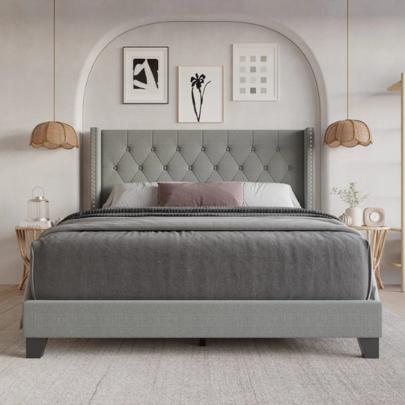Grey upholstered full-size bed with tufted wingback headboard and nailhead trim