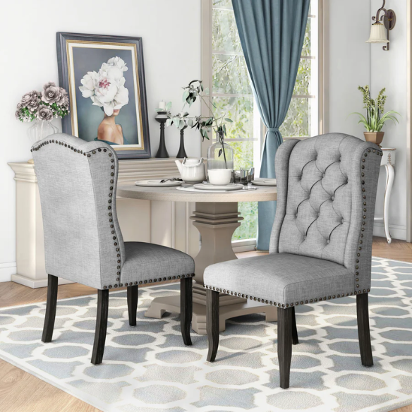 Set of two light grey farmhouse-style wingback dining chairs with button tufting, nailhead trim, and antique black tapered legs