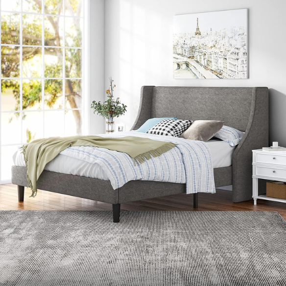 Light grey linen upholstered queen platform bed with wingback headboard, tapered black legs, and slatted support – no box spring needed