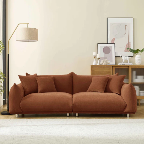 Modern rust upholstered sofa with deep seating and chrome-finished legs, featuring 4 matching accent pillows, perfect for contemporary living rooms.