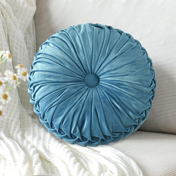 Muted blue velvet round throw pillows with pleated detailing and button center, 14.5-inch set of two styled on a neutral-toned sofa.