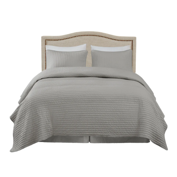 Natural beige upholstered king headboard with curved silhouette, silver nailhead trim, and adjustable metal legs for bed frame mounting