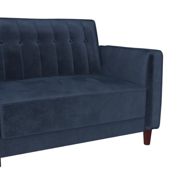 Navy blue velvet convertible sofa with vertical tufting, square arms, and brown tapered legs, designed with a split-back reclining feature and twin bed conversion.